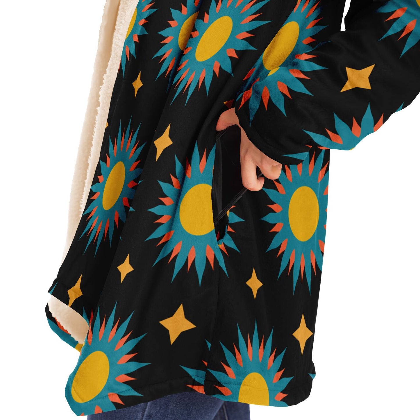 Woman putting a cell phone in the deep pocket of a black microfleece cloak with a colorful sun design.