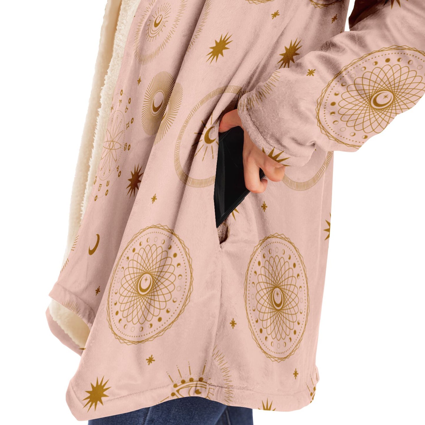 Woman putting a cell phone in the deep pocket of a light pink microfleece cloak with gold cosmic zodiac design