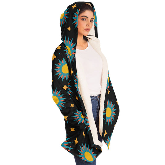 Woman wearing a cozy, hooded, black microfleece cloak with a colorful sun design.