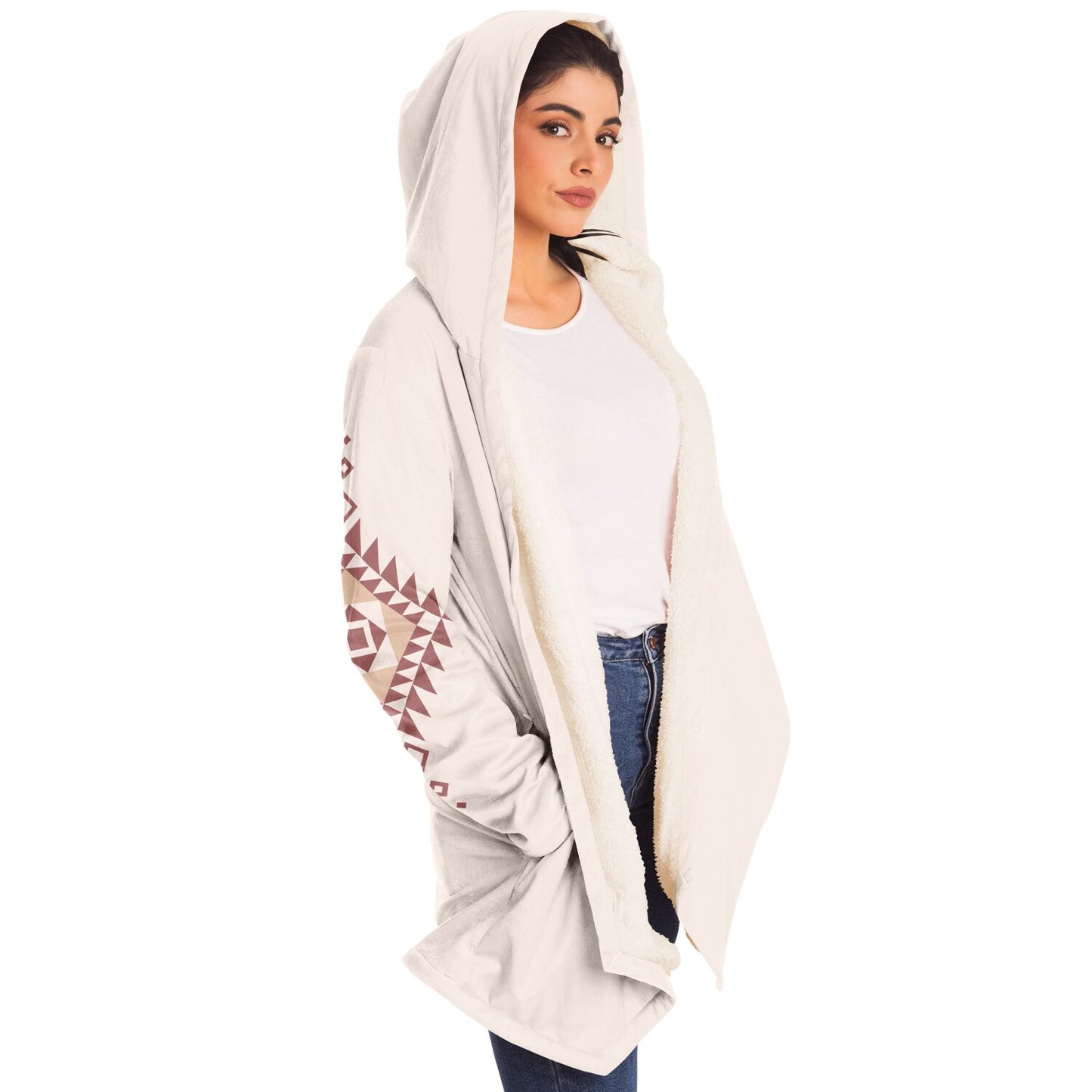 Woman wearing a cozy, hooded, beige microfleece cloak with a pink and tan Southwestern diamond shaped design on the back and elbows.
