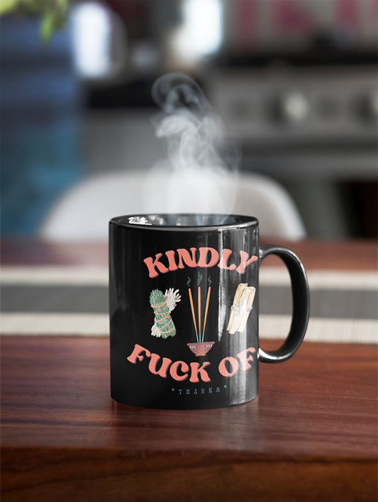 Black mug that says Kindly Fuck Off with sage, palo santo, and incense.