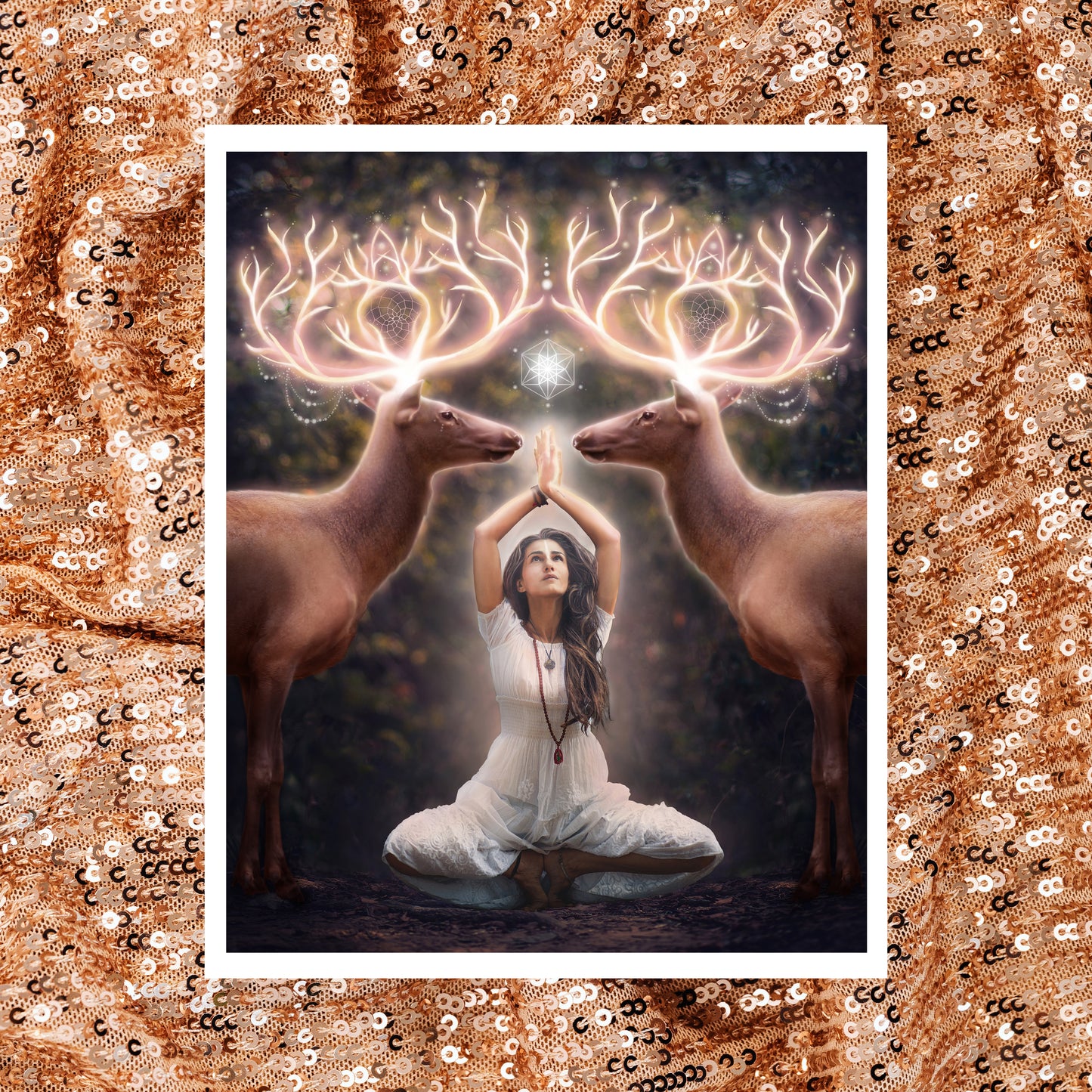 Two elk with glowing antlers stand on either side of a woman meditating in the forest.