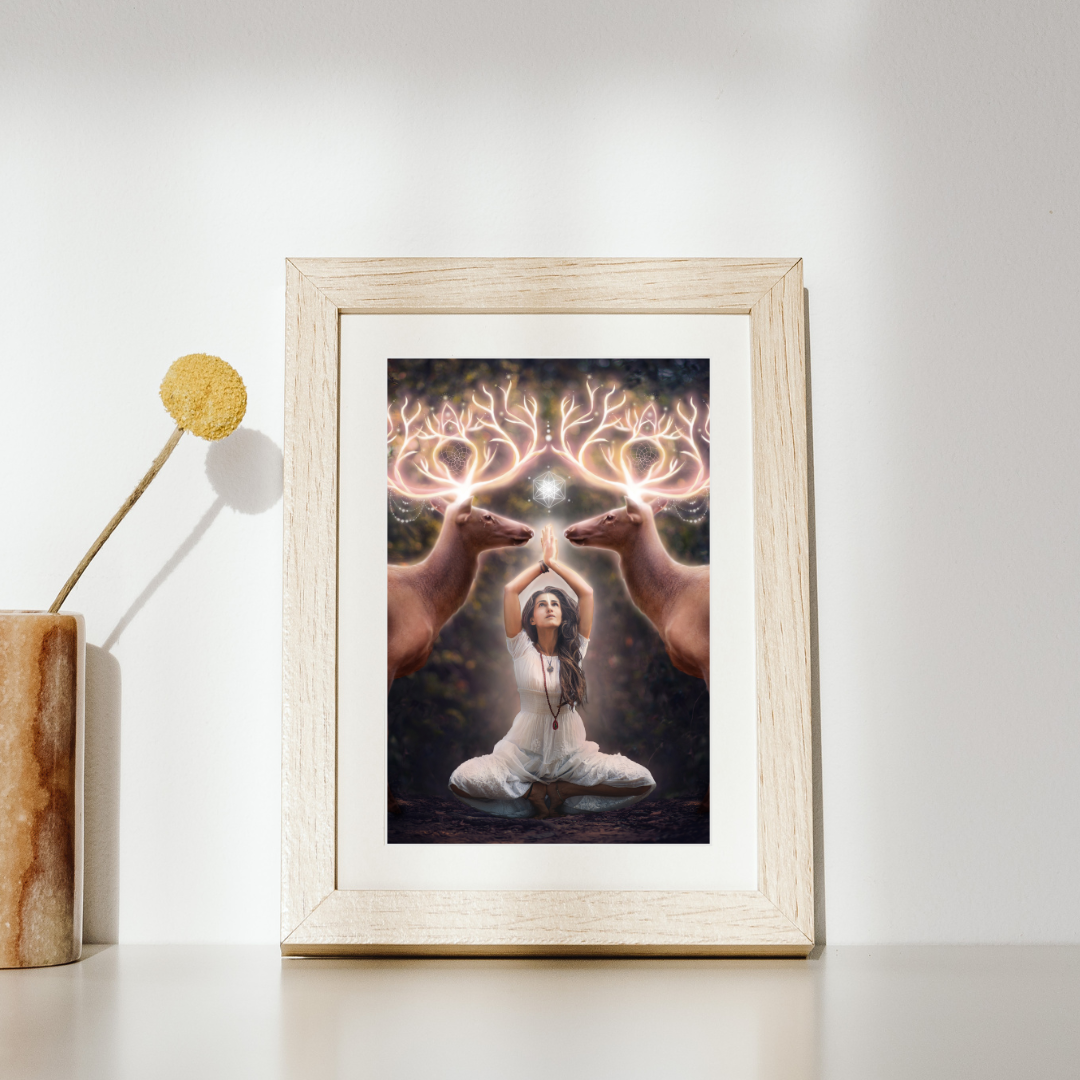 Two elk with glowing antlers stand on either side of a woman meditating in the forest.