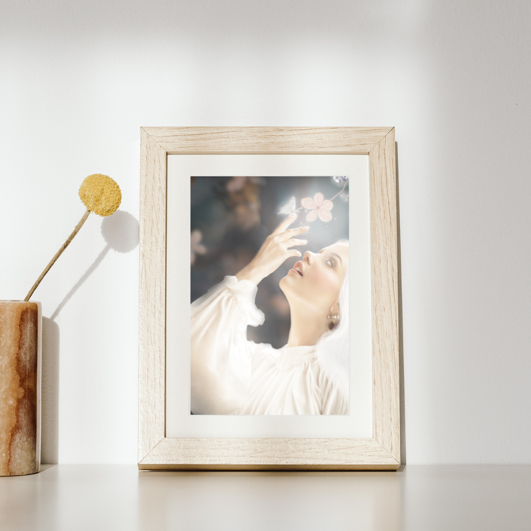 Woman in white reaching towards flowers with a glowing butterfly on her finger.